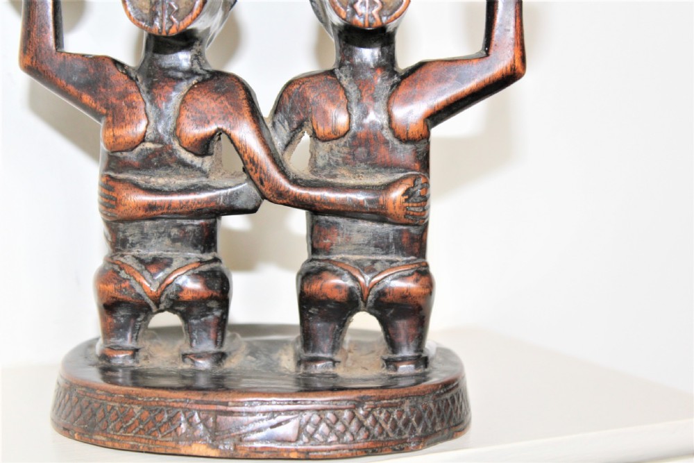 A carved dark hardwood headrest supported by two standing female caryatid figures on a circular carved base. View VII