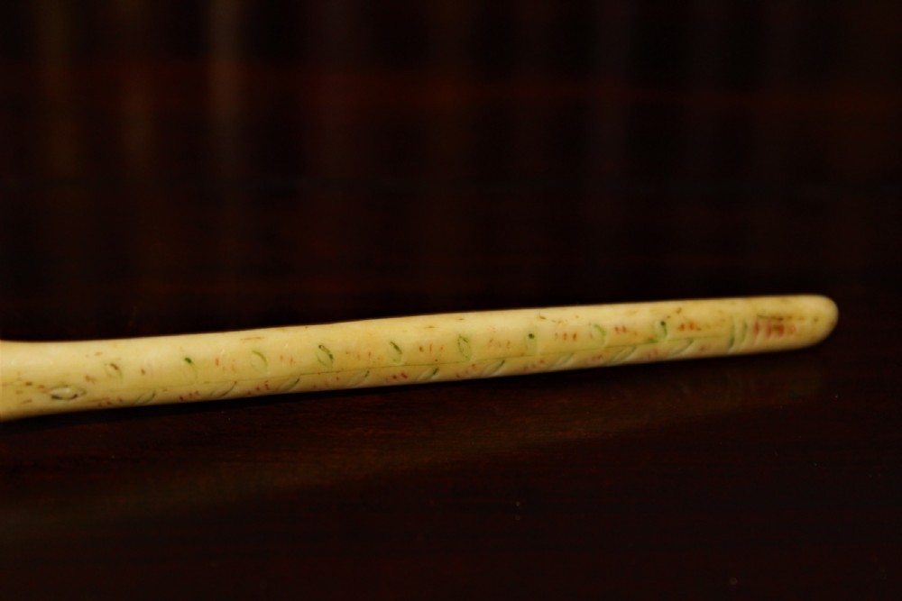 A hand-carved cream bone marrow spoon featuring an engraved date of 1776 and decorative foliage motifs along its handle. View III