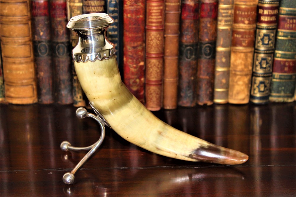 A Victorian candlestick made from a curved natural horn with a polished silver sconce rim and silver ball-footed tripod legs.