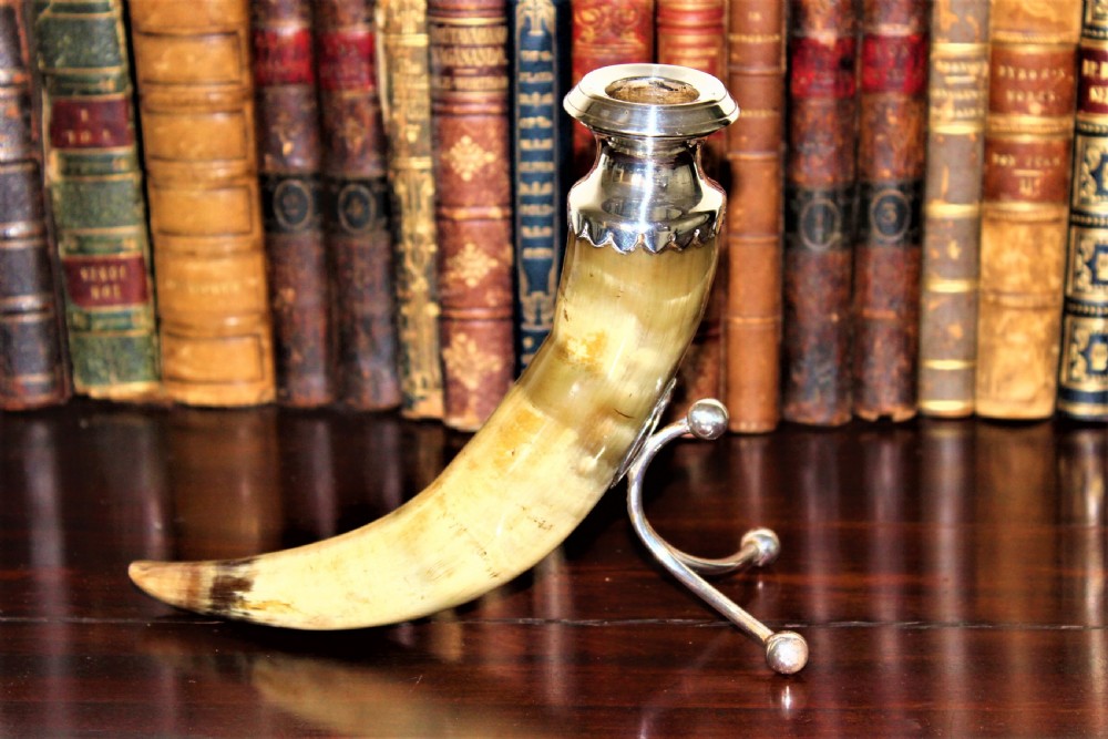 A Victorian candlestick made from a curved natural horn with a polished silver sconce rim and silver ball-footed tripod legs. View II