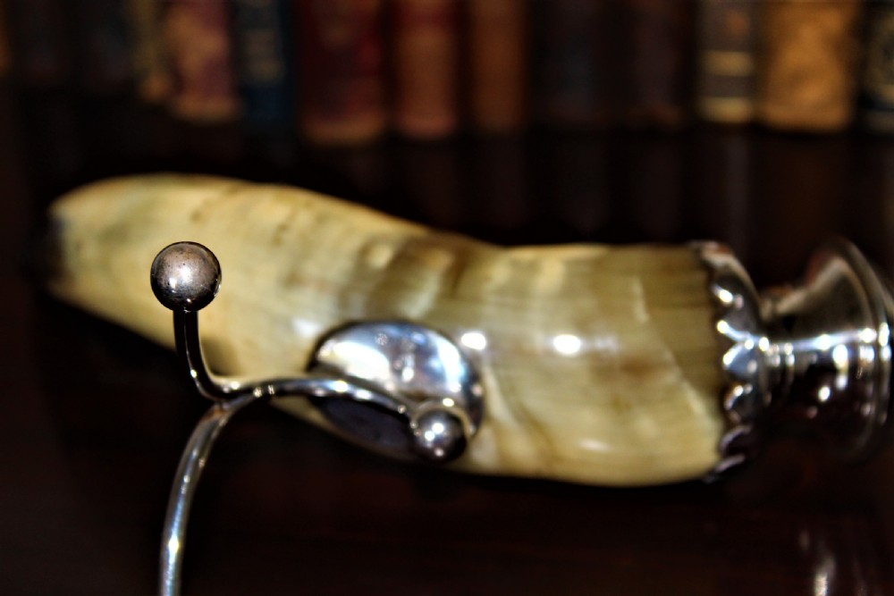 A Victorian candlestick made from a curved natural horn with a polished silver sconce rim and silver ball-footed tripod legs. View VI