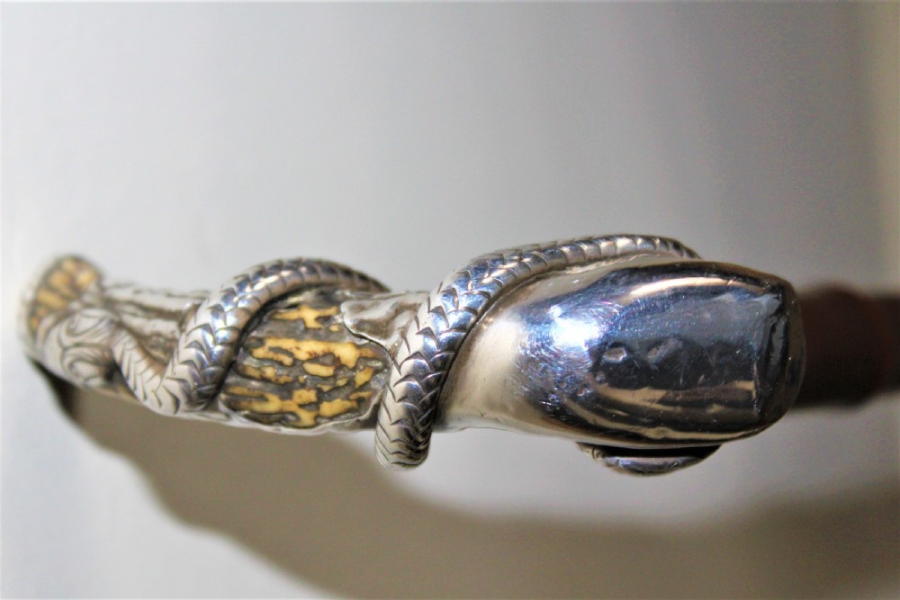 A superb bamboo walking stick the top depicting a finely cast silver snake coiled around a stag horn  Circa 1880 View V