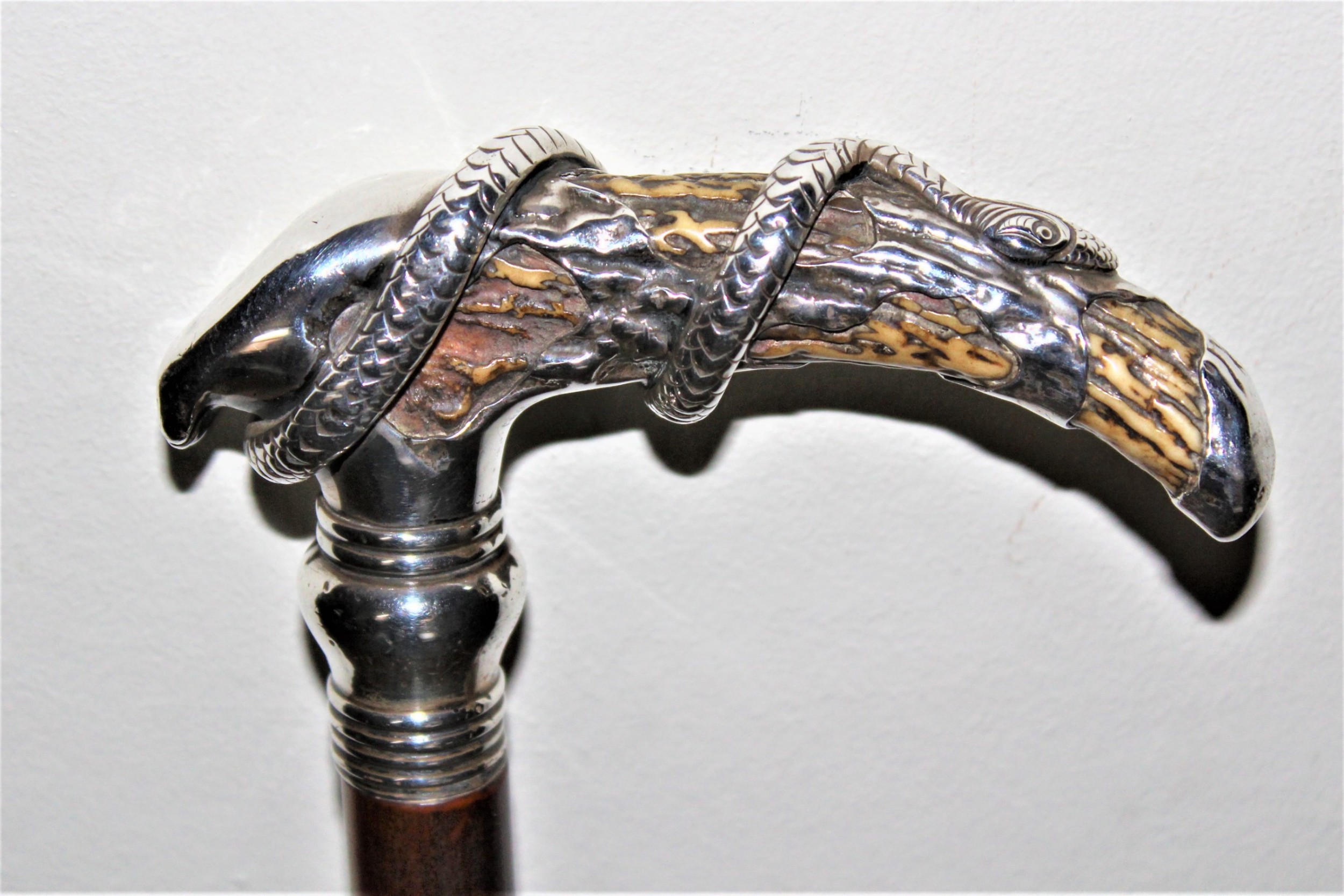 A superb bamboo walking stick the top depicting a finely cast silver snake coiled around a stag horn  Circa 1880
