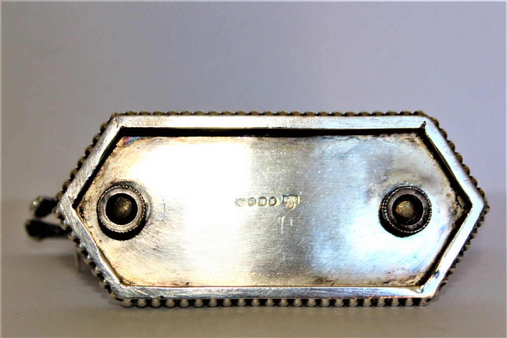 A pair of silver-plated knife rests featuring rampant lions holding shields mounted on beaded rectangular bases. View VI