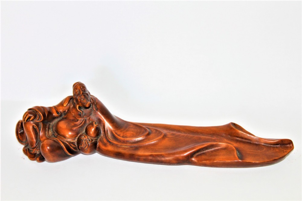 A carved Chinese boxwood wrist rest depicting a reclining bearded sage with flowing robes and a gourd bottle.