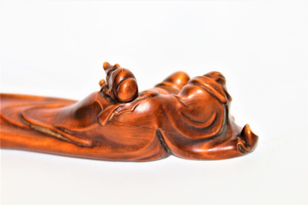 A carved Chinese boxwood wrist rest depicting a reclining bearded sage with flowing robes and a gourd bottle. View IV