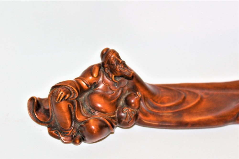 A carved Chinese boxwood wrist rest depicting a reclining bearded sage with flowing robes and a gourd bottle. View VI