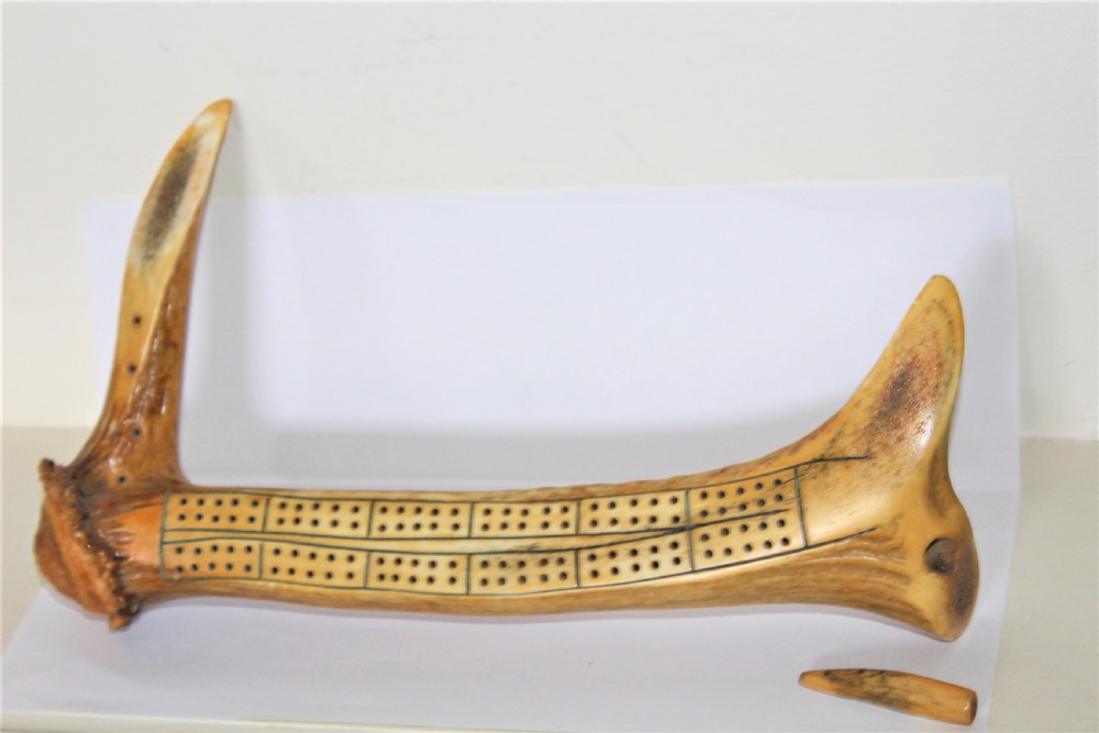 An antique cribbage board crafted from a natural stag antler featuring drilled scoring holes and incised lines. View II