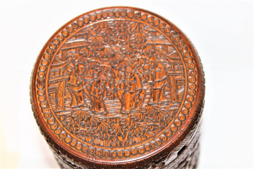 A cylindrical bamboo box covered in detailed high-relief carvings of figures and buildings. View VIII