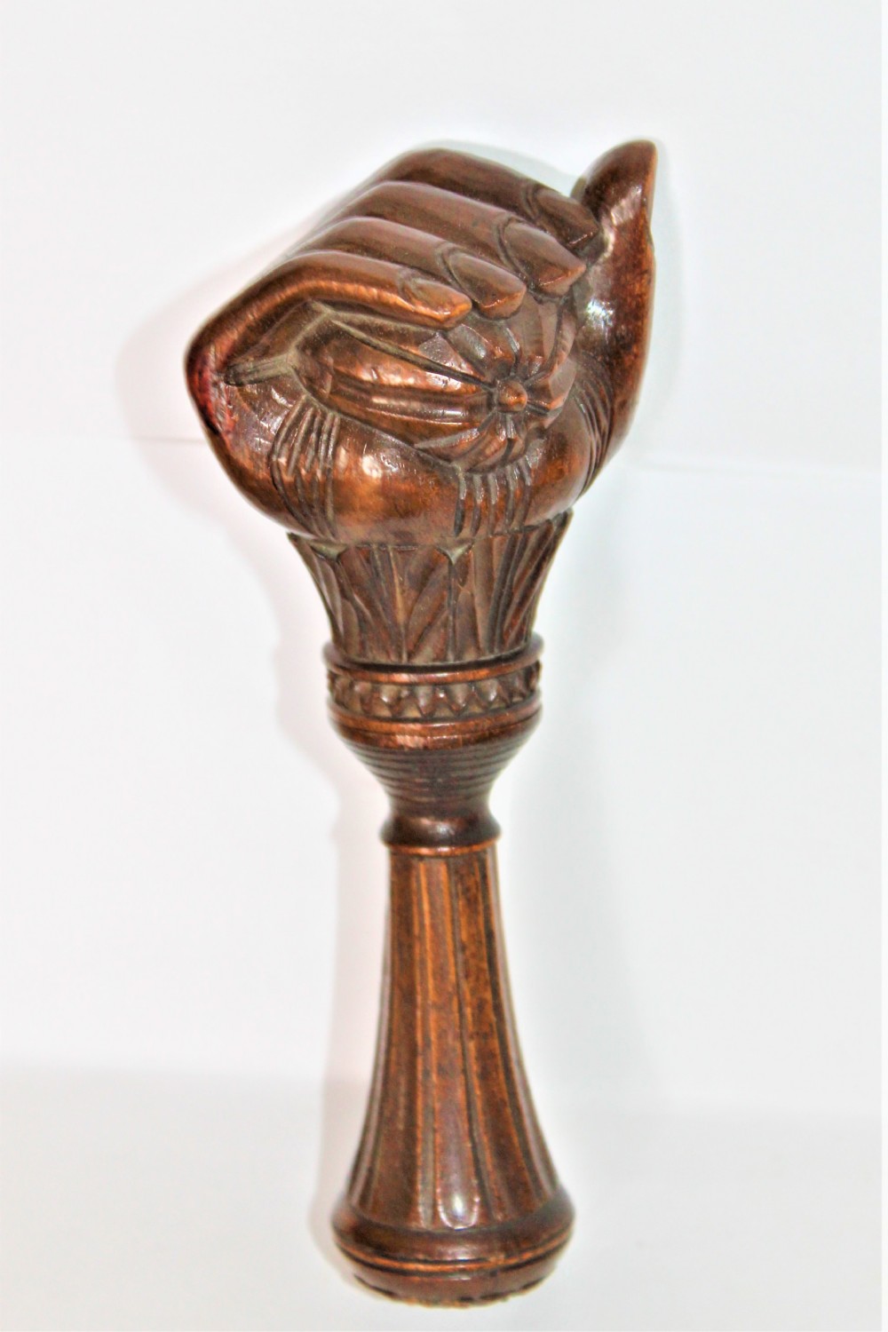 A dark brown hand-carved wooden screw-action nutcracker shaped as a clenched fist.