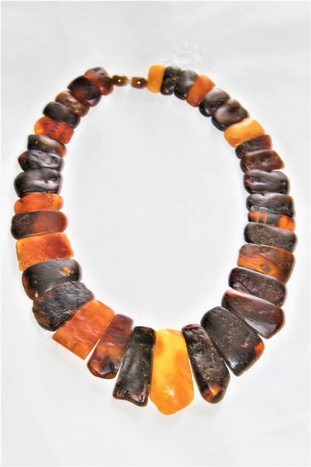 A strand of polished, rectangular amber beads in varying shades of honey, cognac, and dark cherry.