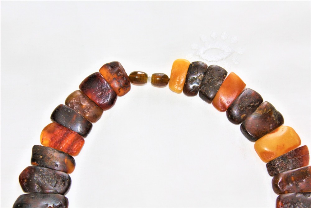 A strand of polished, rectangular amber beads in varying shades of honey, cognac, and dark cherry. View IV