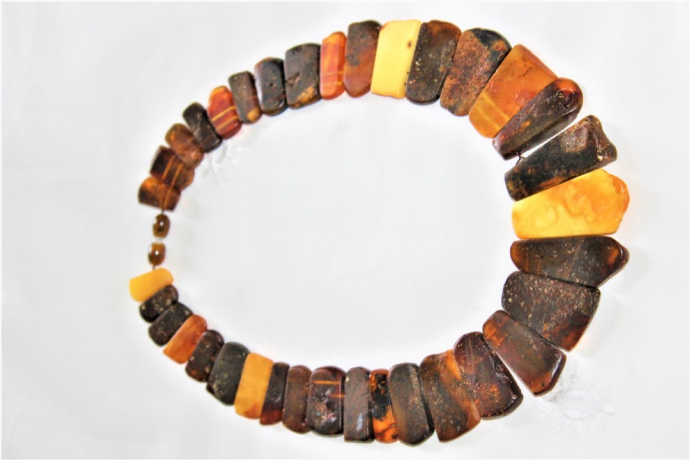 A strand of polished, rectangular amber beads in varying shades of honey, cognac, and dark cherry. View V