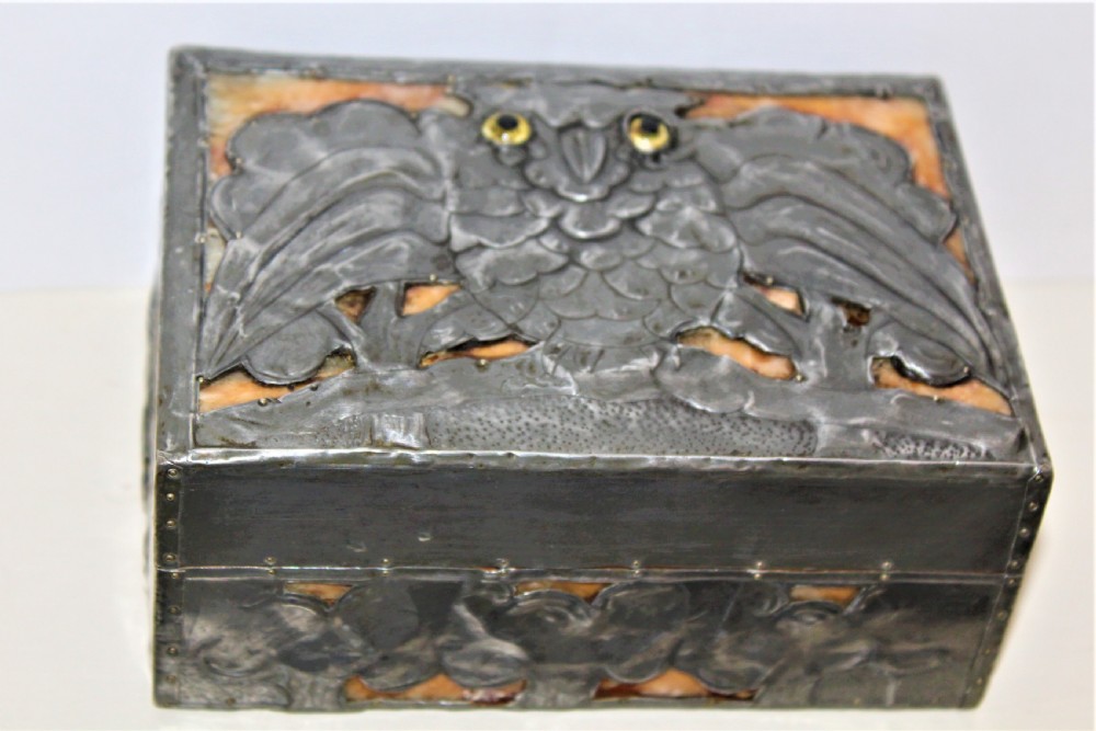 A rectangular Arts and Crafts pewter box featuring a raised repousse owl design with yellow glass eyes on the lid.