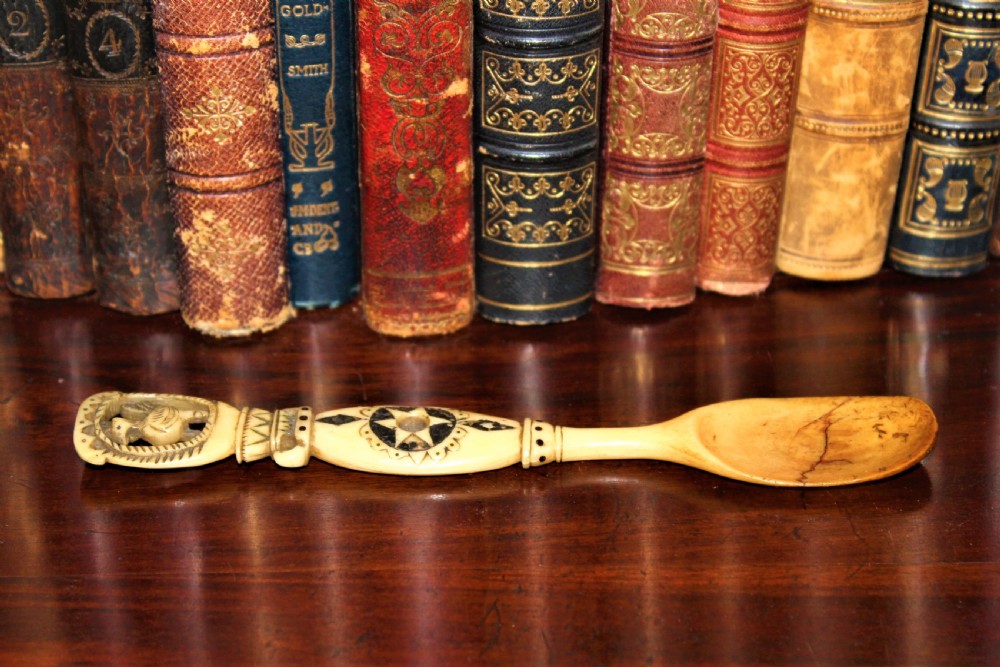An 18th-century Central European carved stag horn love spoon featuring black geometric engravings and a bird motif cut-out on the handle. View IV