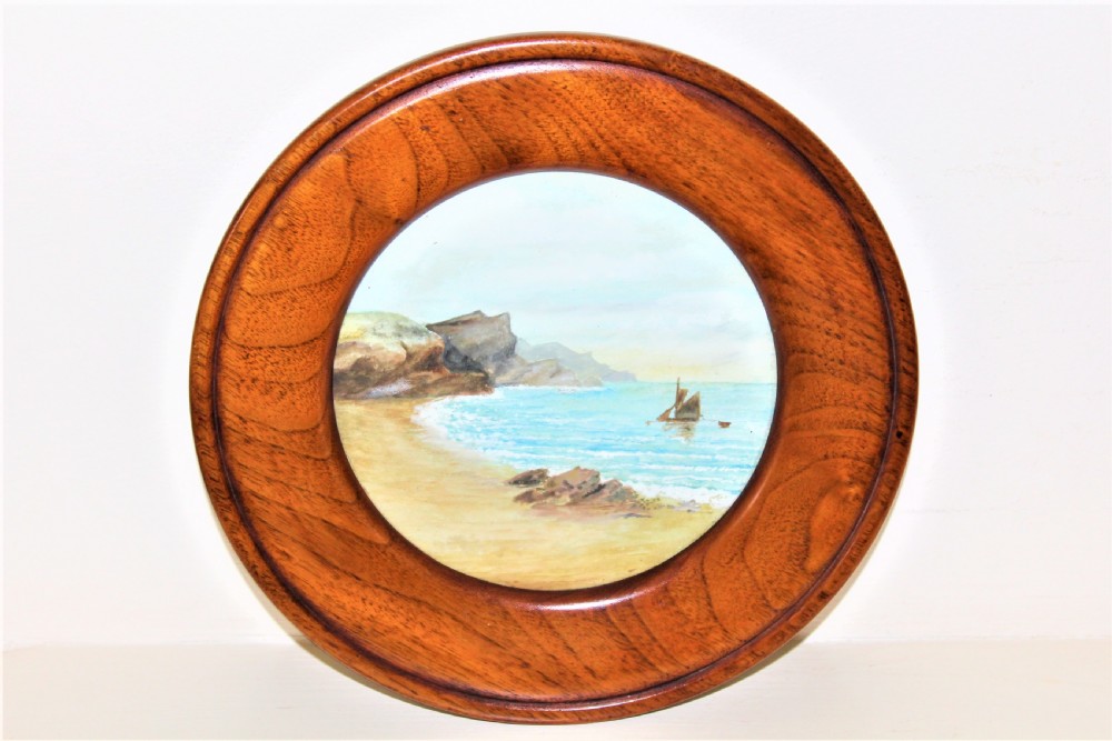 A pair of circular watercolour paintings depicting coastal landscapes with boats and cliffs, set inside polished wood circular frames. View II