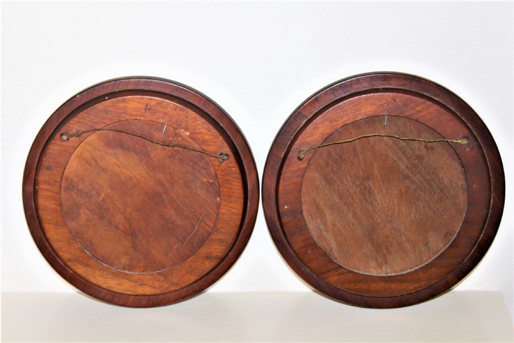 A pair of circular watercolour paintings depicting coastal landscapes with boats and cliffs, set inside polished wood circular frames. View VI