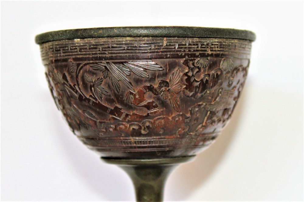 A footed Chinese goblet featuring a dark brown carved coconut shell bowl mounted on a slender pewter stem and circular base. View IV