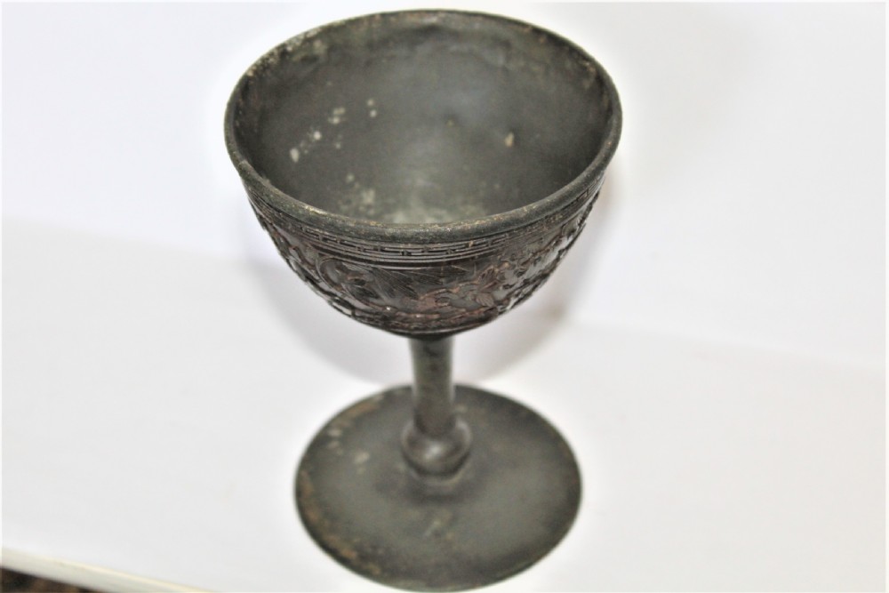A footed Chinese goblet featuring a dark brown carved coconut shell bowl mounted on a slender pewter stem and circular base. View V