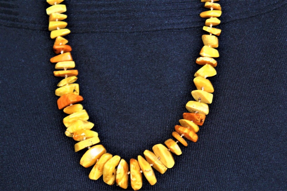 A long single strand of irregularly shaped natural amber beads displaying varied tones from pale butterscotch to warm golden honey. View III