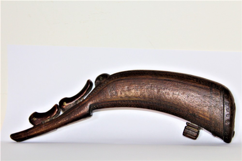 A curved 18th-century carved dark horn powder flask featuring decorative zoomorphic terminal detailing and brass eye inserts. View III