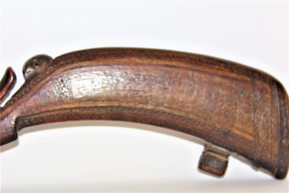 A curved 18th-century carved dark horn powder flask featuring decorative zoomorphic terminal detailing and brass eye inserts. View V