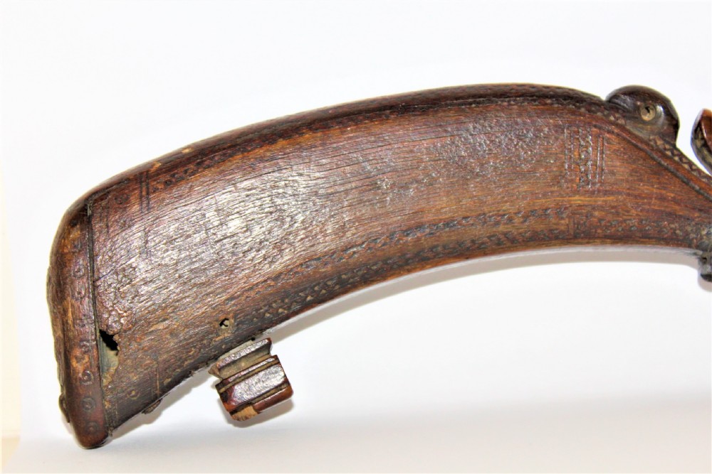 A curved 18th-century carved dark horn powder flask featuring decorative zoomorphic terminal detailing and brass eye inserts. View VI