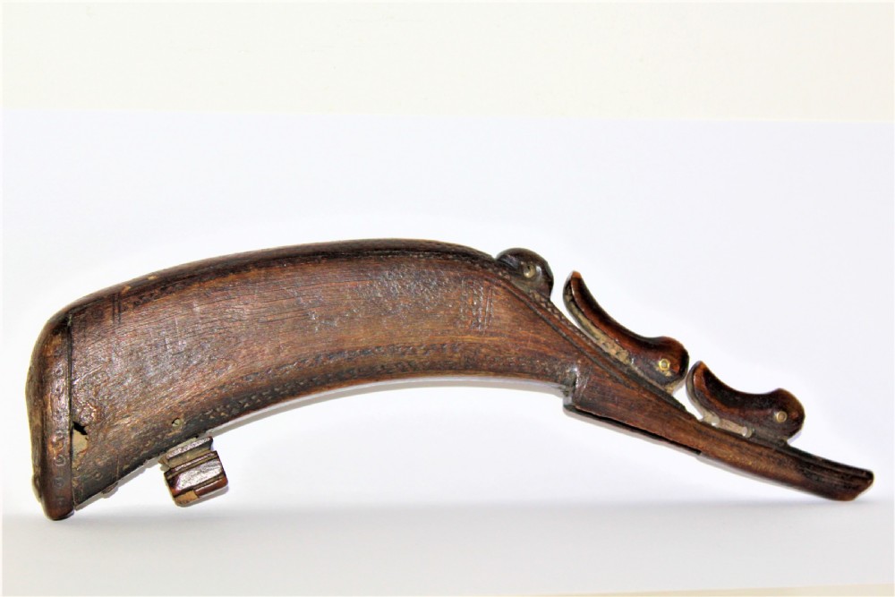 A curved 18th-century carved dark horn powder flask featuring decorative zoomorphic terminal detailing and brass eye inserts. View VIII