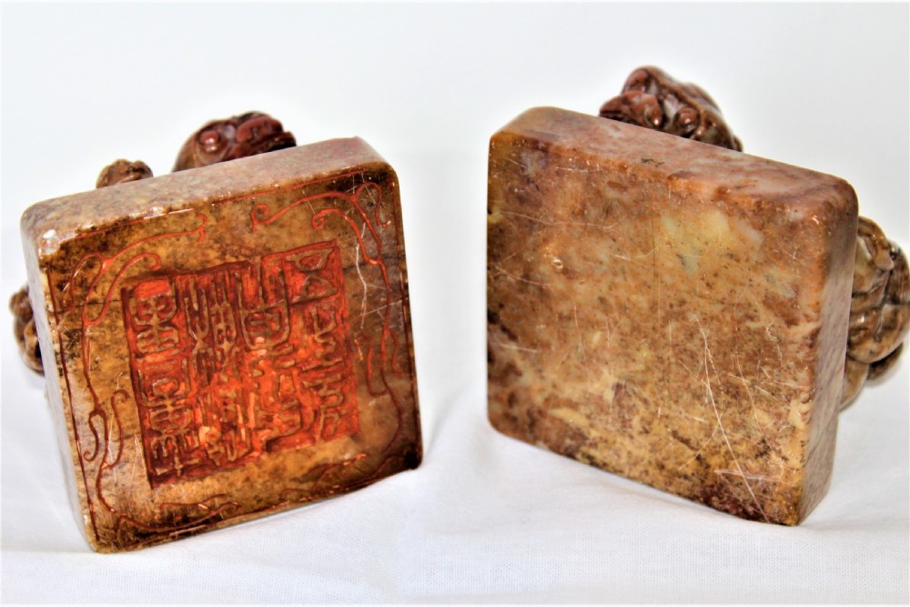 A pair of carved brown and red soapstone desk seals featuring Chinese guardian lions mounted on square plinths. View III