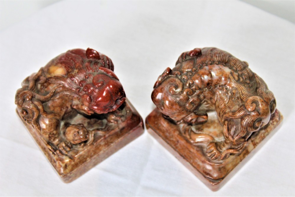 A pair of carved brown and red soapstone desk seals featuring Chinese guardian lions mounted on square plinths. View IV