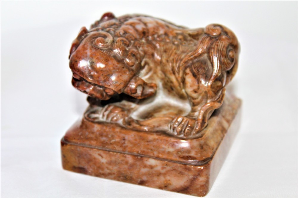 A pair of carved brown and red soapstone desk seals featuring Chinese guardian lions mounted on square plinths. View VI
