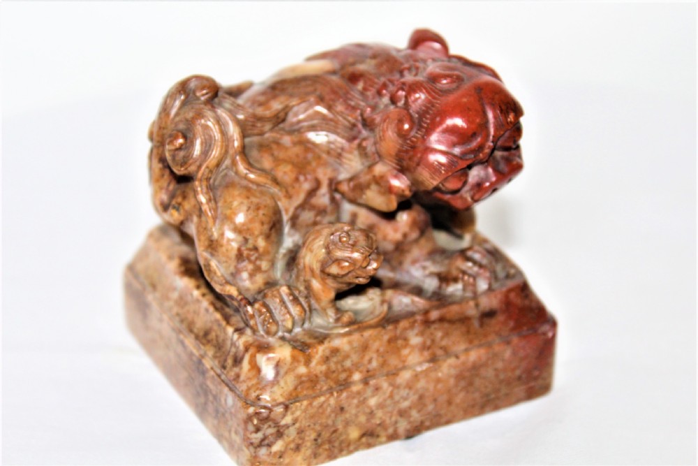 A pair of carved brown and red soapstone desk seals featuring Chinese guardian lions mounted on square plinths. View VII
