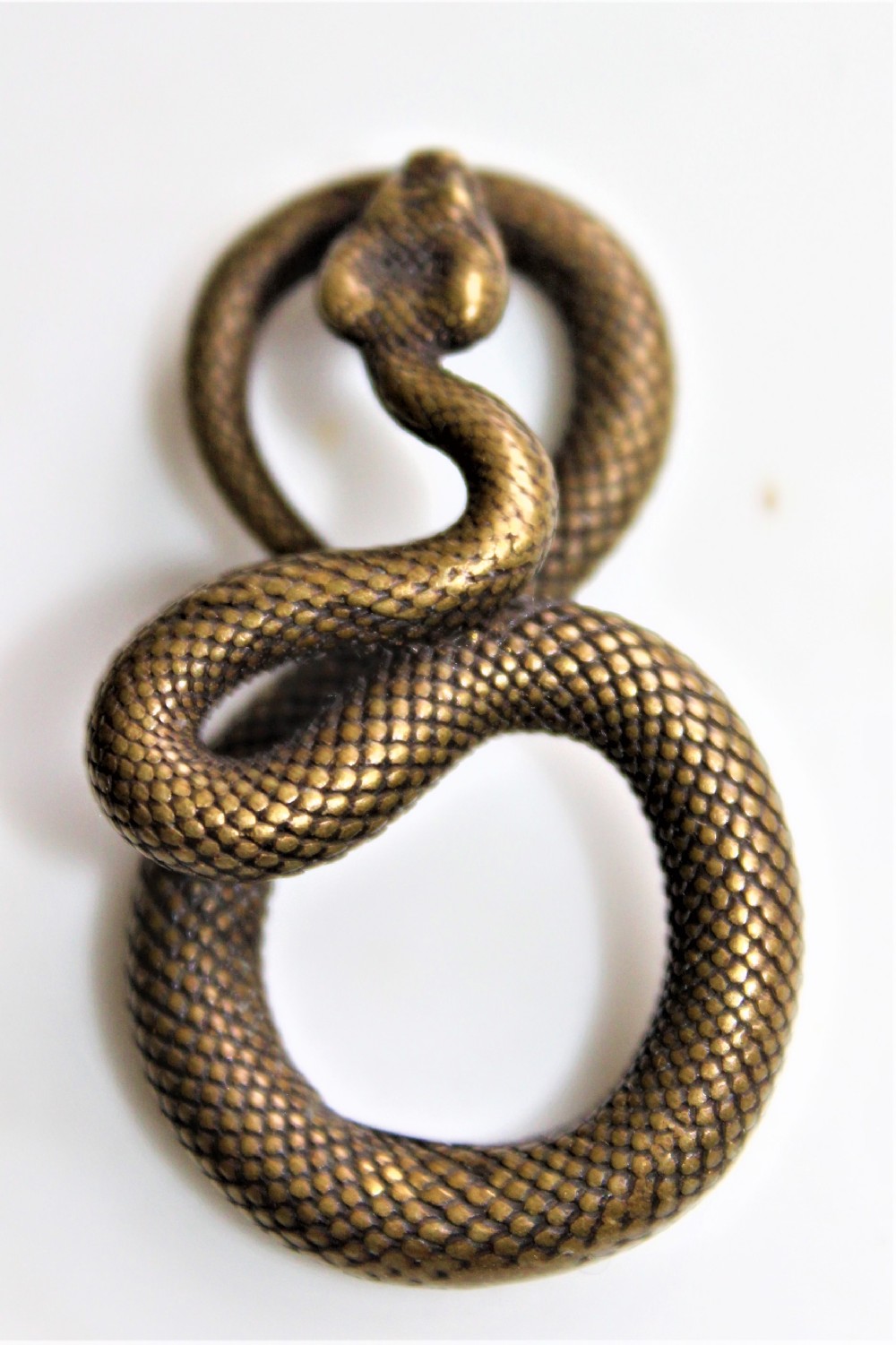 A small well defined bronze pendant in the form of a coiled snake 5cm long by 3 cm wide