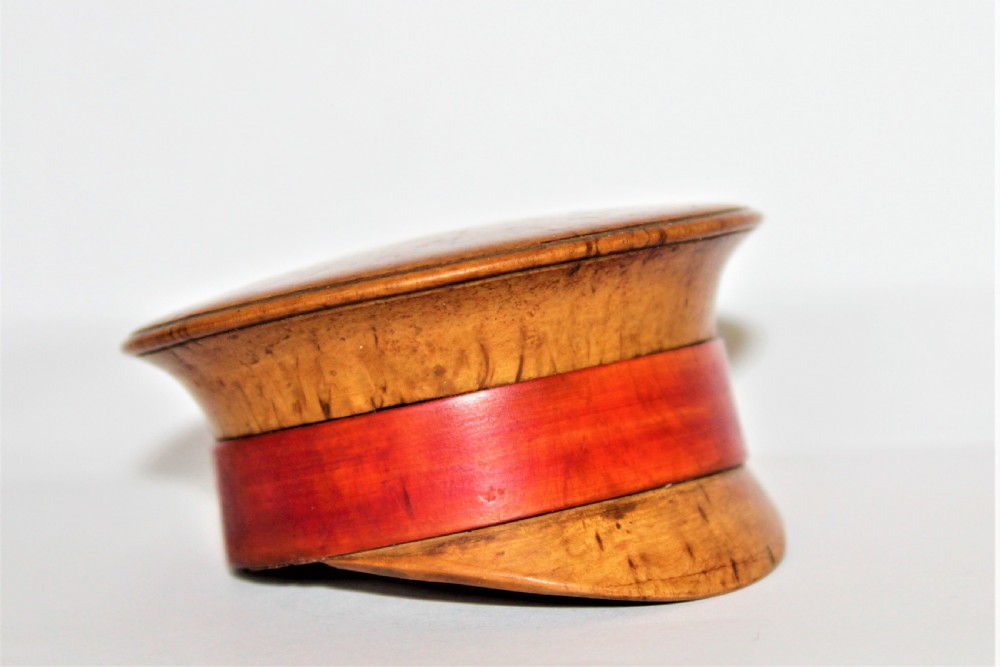 A small turned burr walnut novelty snuff box shaped like a military cap featuring a red painted central band. View III