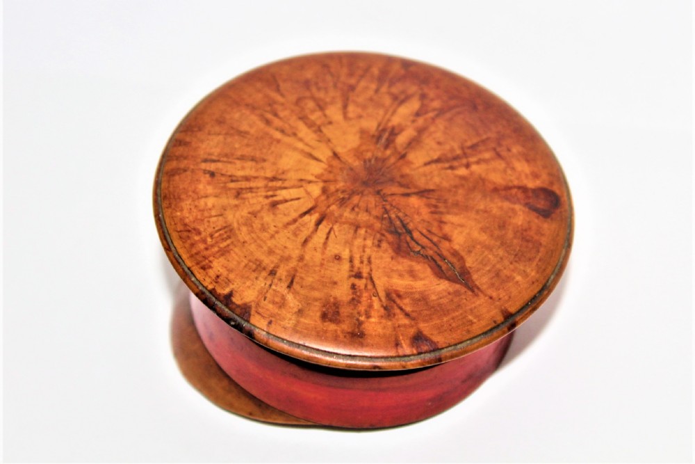 A small turned burr walnut novelty snuff box shaped like a military cap featuring a red painted central band. View IV