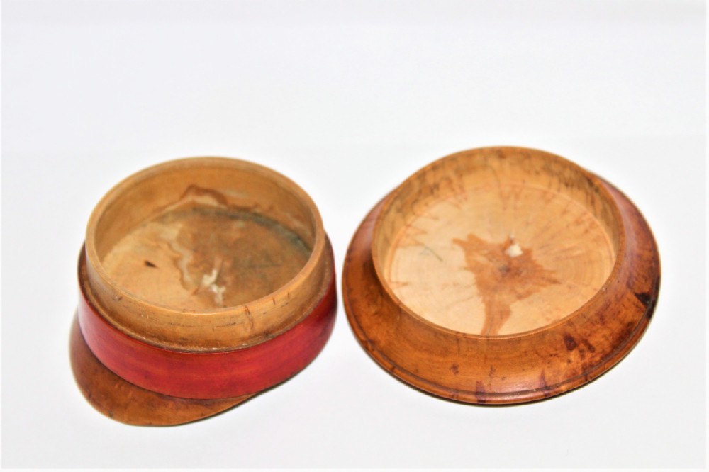 A small turned burr walnut novelty snuff box shaped like a military cap featuring a red painted central band. View V