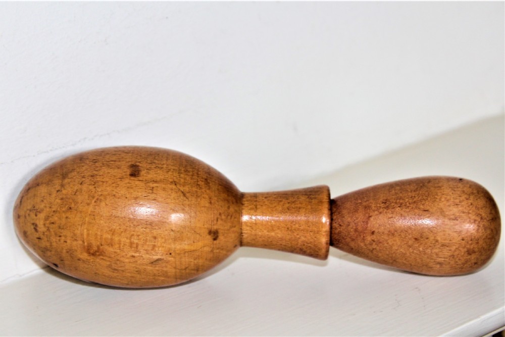 A double-ended turned wooden sock darner with two different sized rounded ends connected by a central neck.