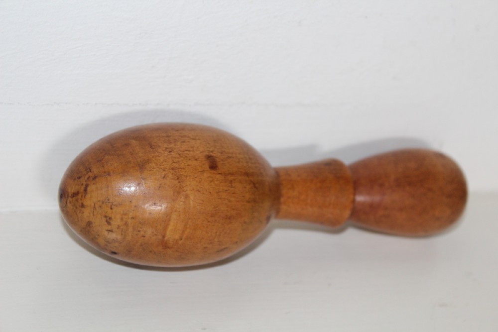 A double-ended turned wooden sock darner with two different sized rounded ends connected by a central neck. View II