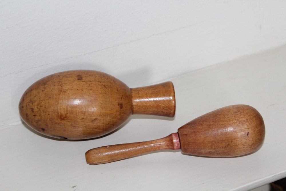 A double-ended turned wooden sock darner with two different sized rounded ends connected by a central neck. View III