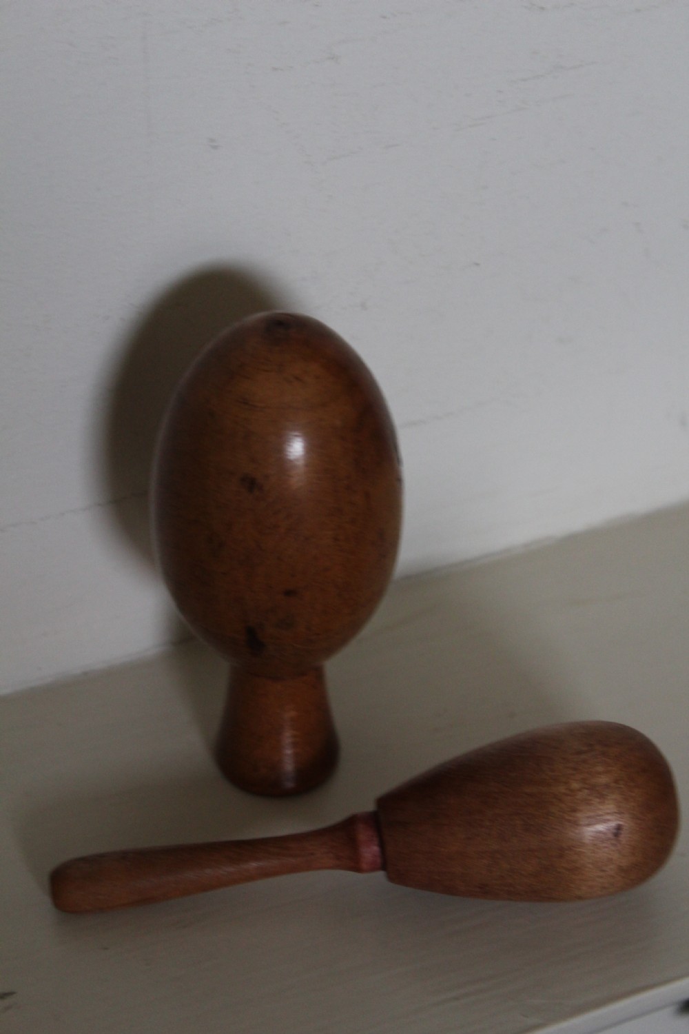 A double-ended turned wooden sock darner with two different sized rounded ends connected by a central neck. View IV