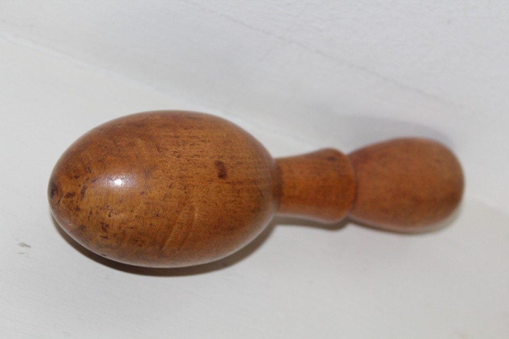 A double-ended turned wooden sock darner with two different sized rounded ends connected by a central neck. View VI