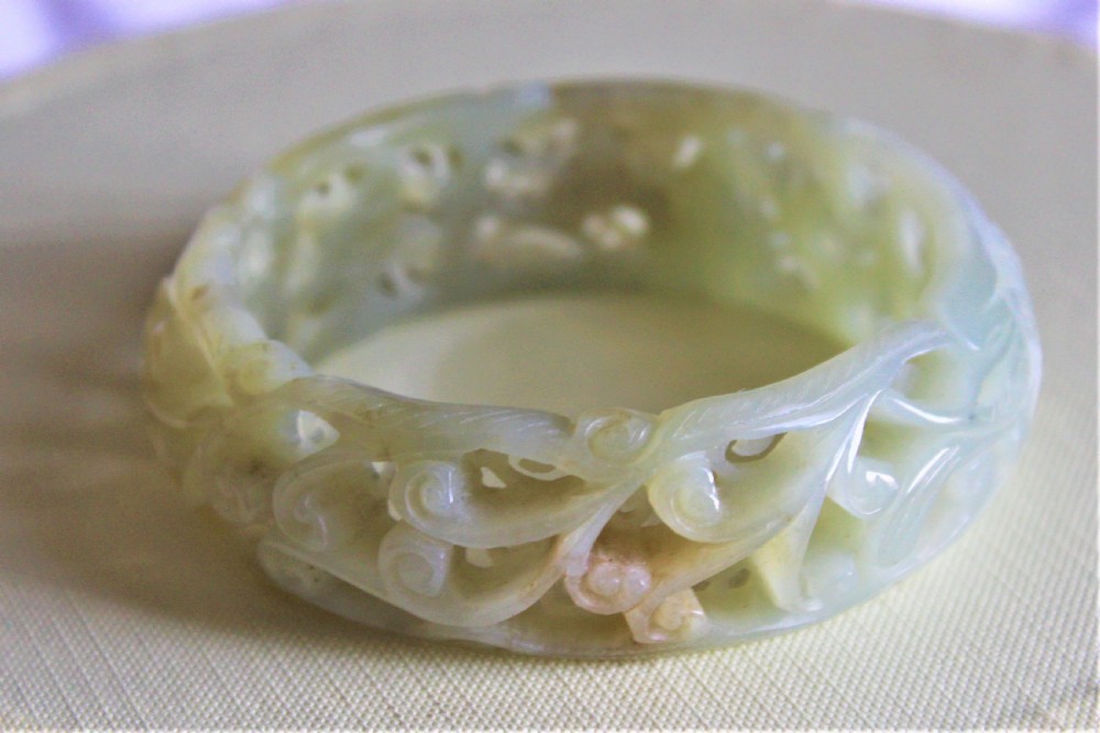 A very fine and deeply carved Chinese celadon jade bangle 