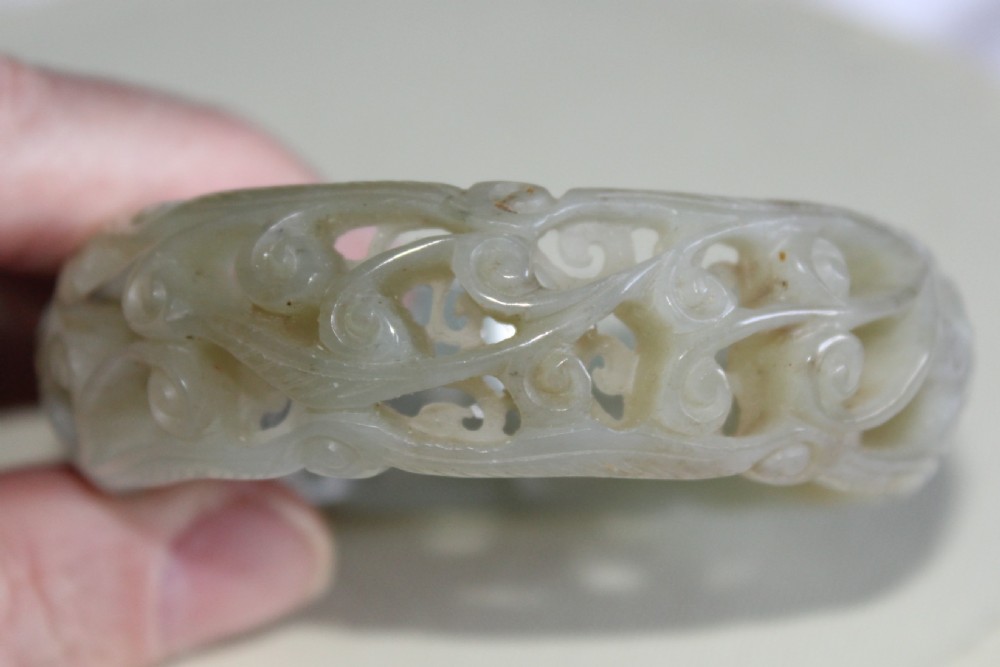A very fine and deeply carved Chinese celadon jade bangle  View III