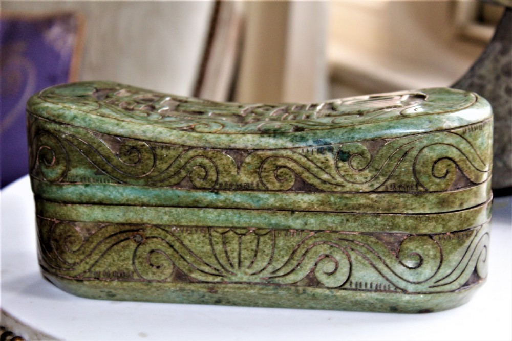 A carved light green hardstone Chinese pillow box with decorative scrollwork and carved characters on the concave upper surface. View III