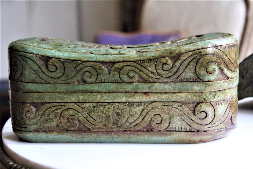 A carved light green hardstone Chinese pillow box with decorative scrollwork and carved characters on the concave upper surface. View IV