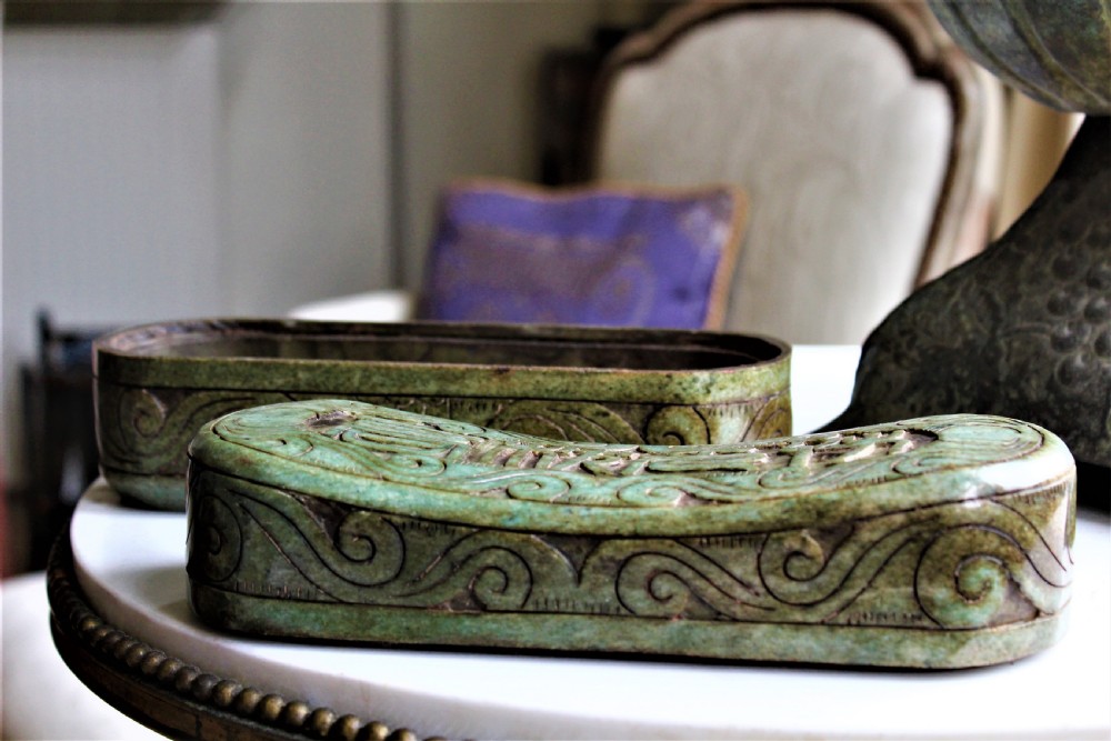 A carved light green hardstone Chinese pillow box with decorative scrollwork and carved characters on the concave upper surface. View V