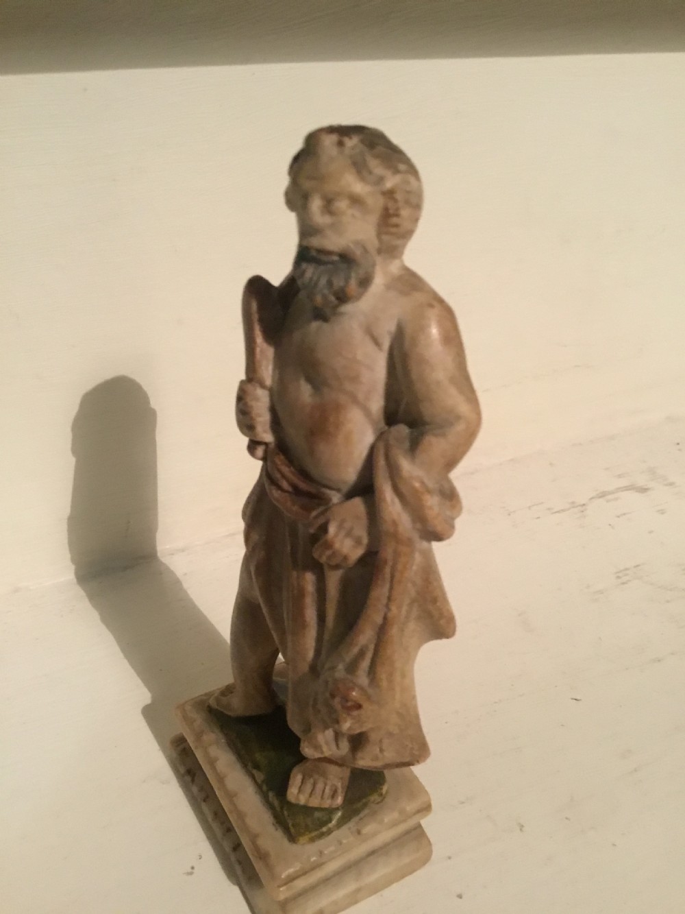 A carved beige marble figure depicting a bearded Roman philosopher in draped robes standing on a moulded plinth base. View IV