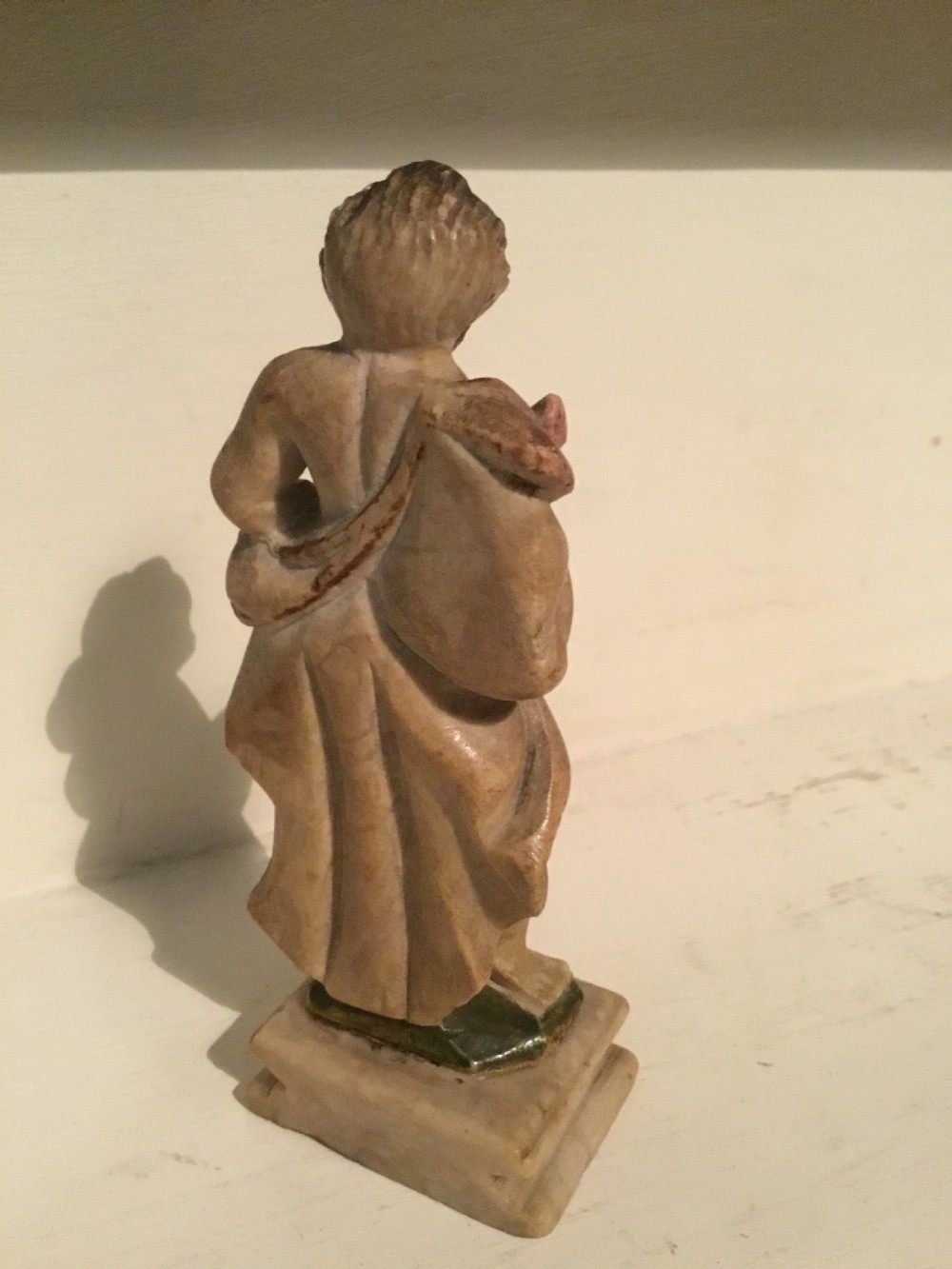 A carved beige marble figure depicting a bearded Roman philosopher in draped robes standing on a moulded plinth base. View V