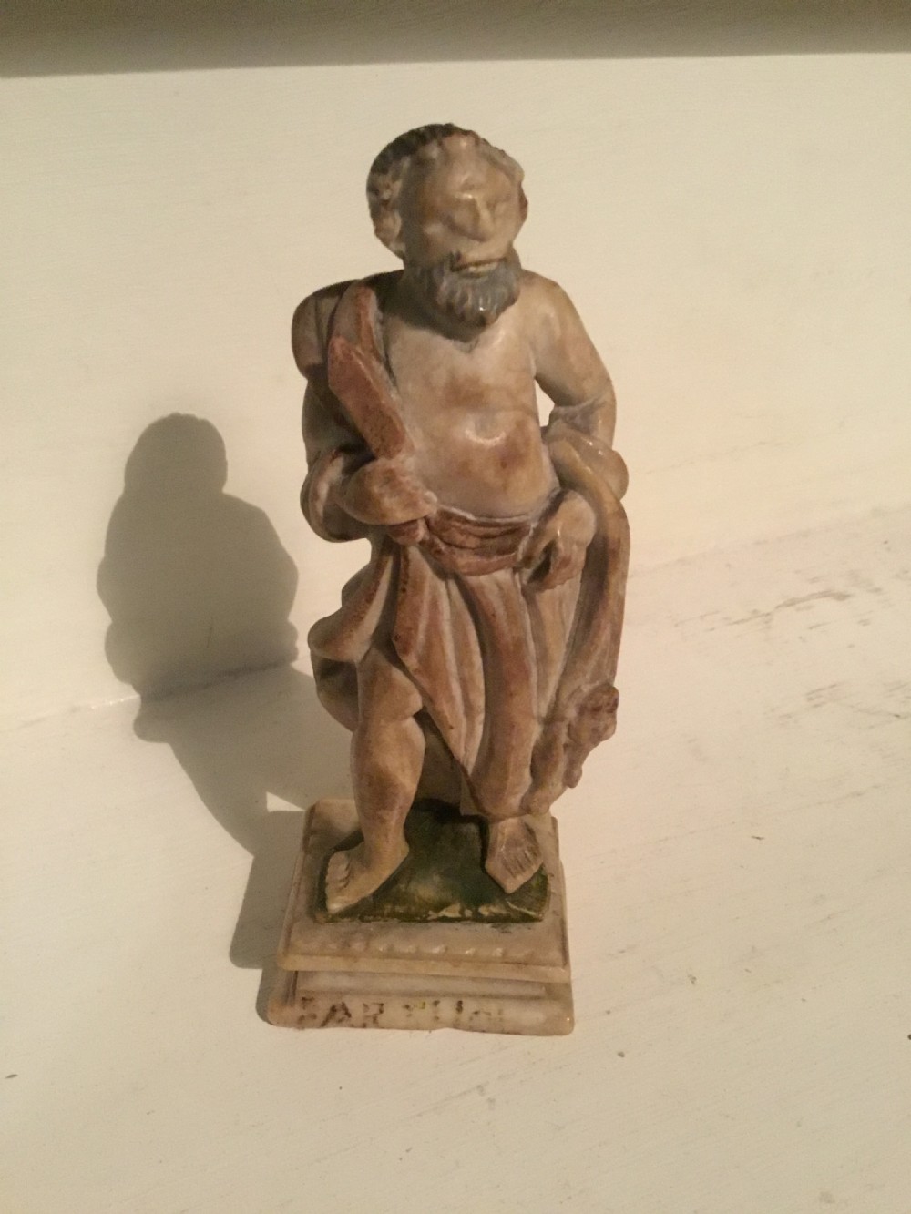 A carved beige marble figure depicting a bearded Roman philosopher in draped robes standing on a moulded plinth base. View VI