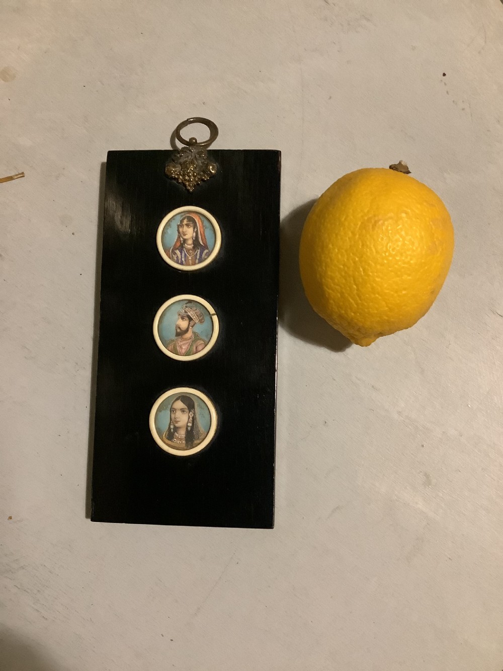 A small Indian ebonised wood painting of three miniatures finely painted on the back of the glass View II